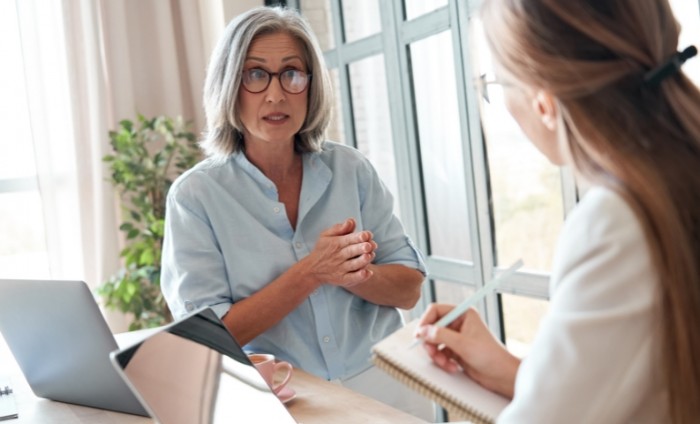 Mature old female mentor or manager training young intern explaining sharing professional skills in office.