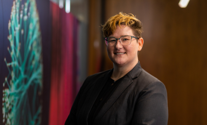 Photo of Dr. Jen Rhymer in front of colourful wall